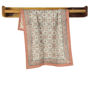 Floral-patterned cotton kitchen towel draped over a wooden rod on a white background