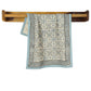 Decorative towel with floral pattern hanging on a wooden towel rack against a white background