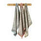 Three patterned cotton kitchen towels hanging from a wooden peg rack against a plain white background.