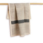 Textured towel with geometric pattern hanging on a wooden rod against a white background