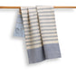 Striped towel with blue and beige pattern draped over a wooden rod on a white background
