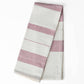 A folded striped fabric item, likely a napkin or tea towel, featuring alternating wide white and dusty rose pink stripes, shown on a clean white background.