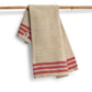 Beige towel with red stripes hanging on a bamboo rod against a white background