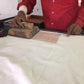 Person in a red shirt using a stamp on a large piece of fabric
