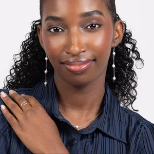 Woman in a blue pleated blouse wearing freshwater pearl triple drop leverback earrings in sterling silver