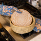 Person wearing oven mitts with a woven basket on a stovetop
