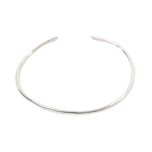 Woman's arm wearing stack of hammered bangles in sterling silver and brass.